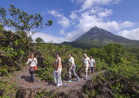 A group of 5 adult hikers walk a trail near the iconic Arenal Volcano in Costa Rica.