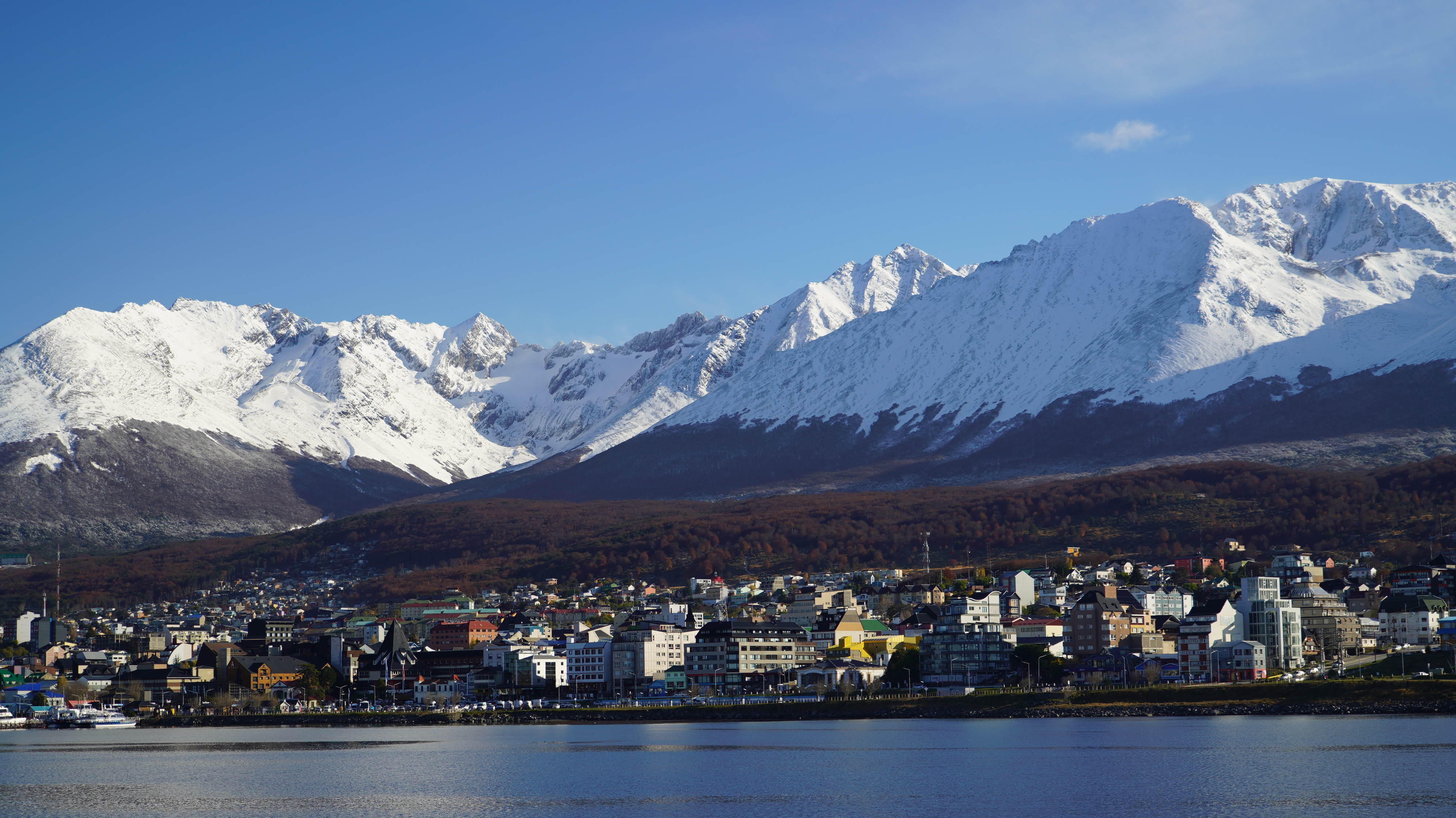 The southermost City of Ushuaia at the "end of the world" in Argentina is seen from the water with snow-capped mountains of Patagonia in the background.