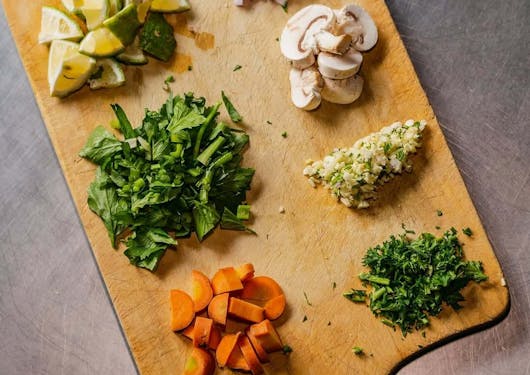 Farm fresh ingredients from Ololo Farm in Kenya are shown in two colorful rows on a wooden serving tray.