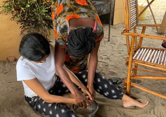 A traveler prepares food with a local lady during a community homestay in Kenya.
