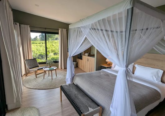A large bed with mosquito nets tied to its posts is shown at an accommodation in Kenya.