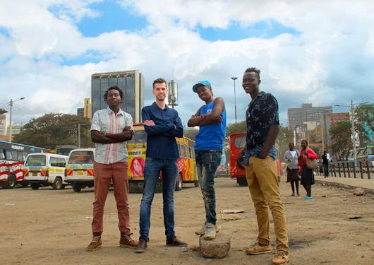 A White traveler poses with 3 Black Kenyan men on a cultural Nai Nami tour of Nairobi.