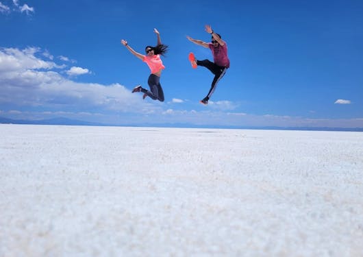 A couple taking a photo and having fun in the Salt Flats in Jujuy.