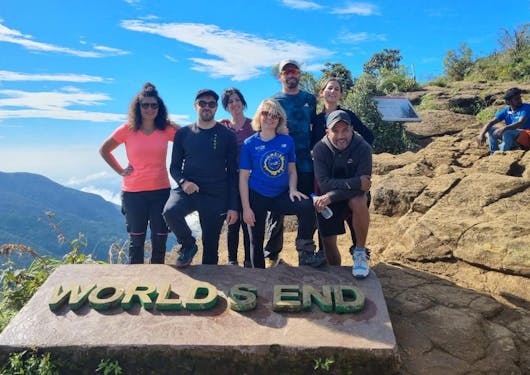 A group of 7 adult trekkers stand at the World's End viewpoint along the Pekoe Trail in Sri Lanka.