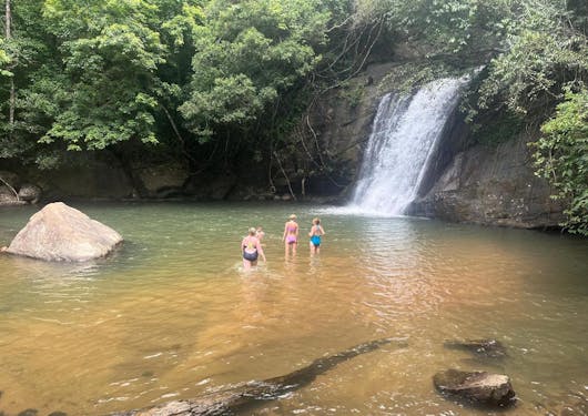 A few people bathe at the base of a flowing waterfall in Sri Lanka.