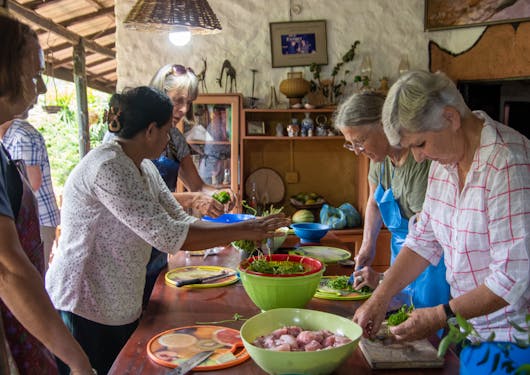 A group of adult women enjoy a cooking class in Sri Lanka led by a local woman.