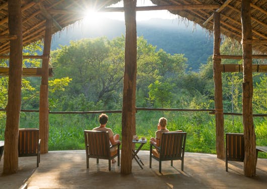 A couple sits on deck chairs looking out over greenery in Sri Lanka.