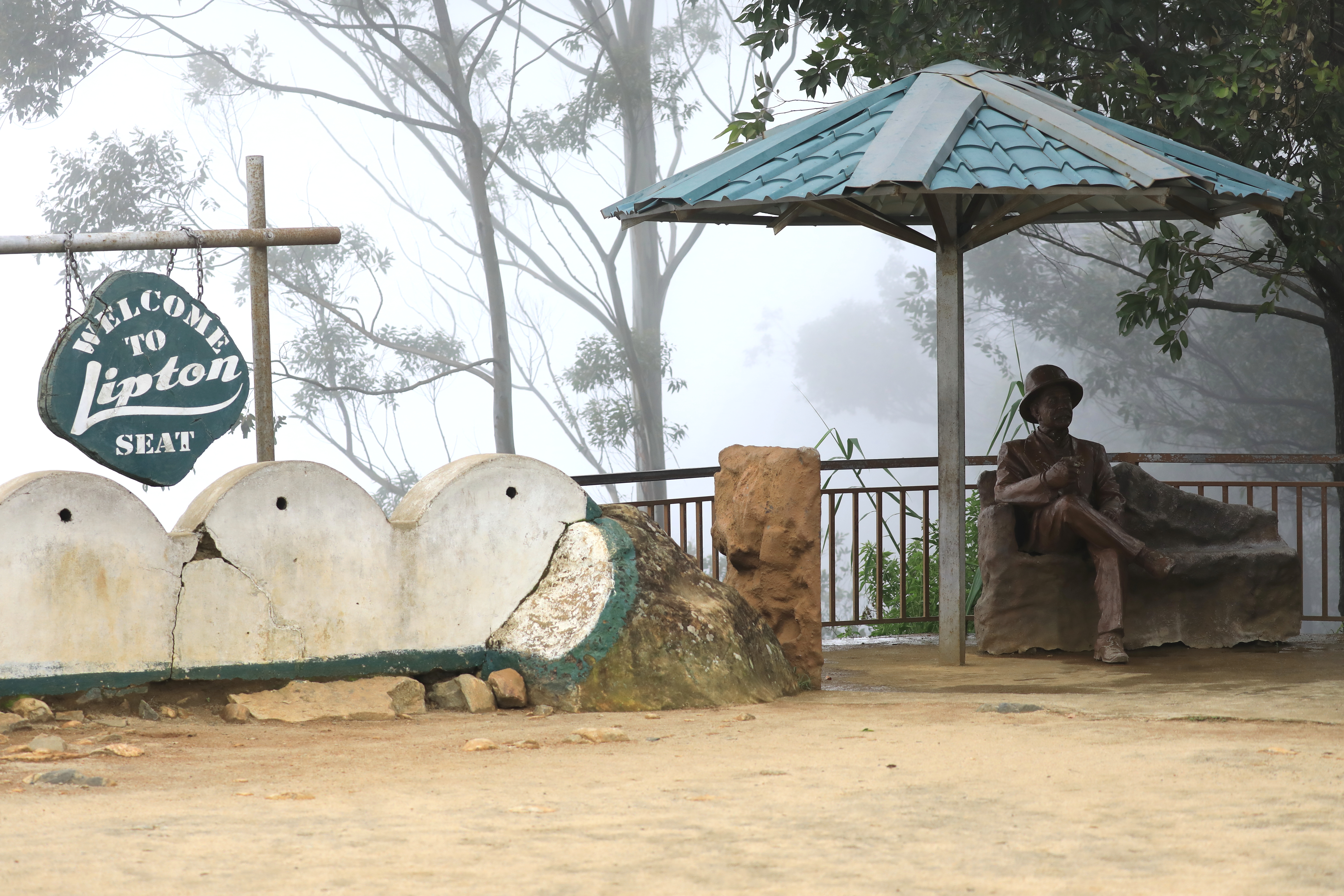 Atop Lipton's Seat, a sign and a statue of Lipton indicate the viewpoint overlooking tea plantations in Sri Lanka.