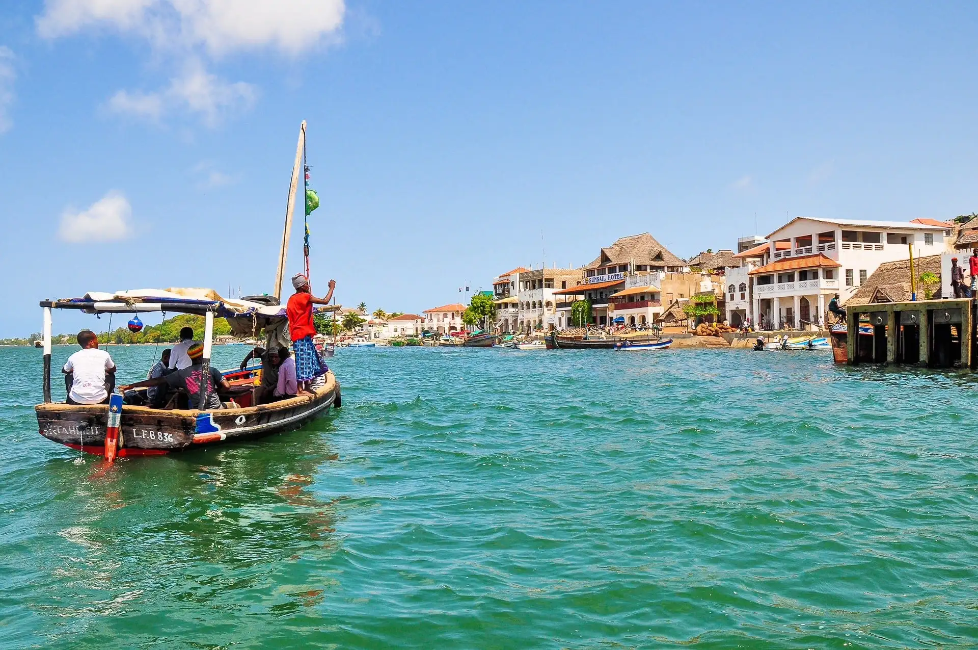 A small boat sails on turquoise waters off the coast of Lamu, Kenya.