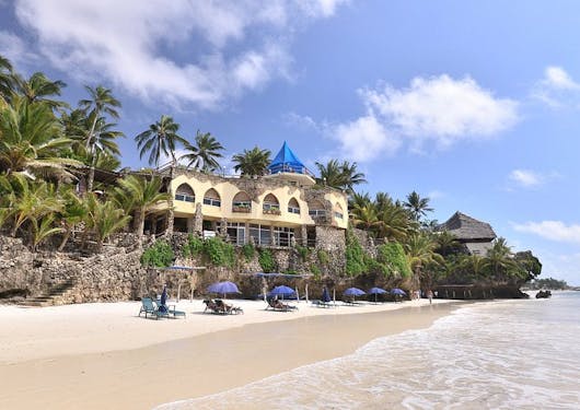 A perched beachfront hotel is shown from the water in Kenya.