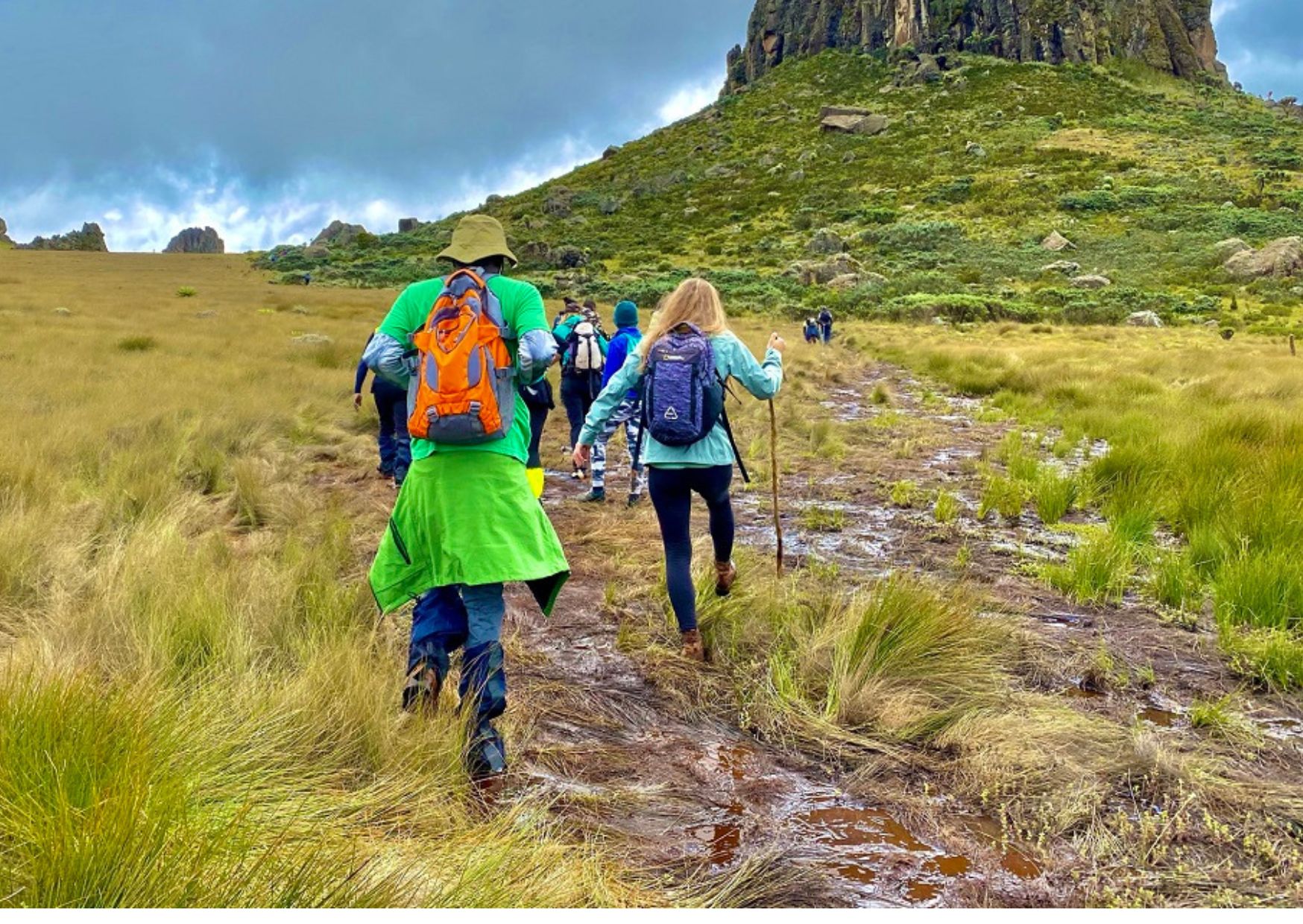 A group of travelers in Kenya in bright clothing on a walk over some grassland.