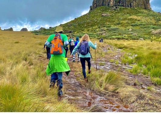A group of travelers in Kenya in bright clothing on a walk over some grassland.