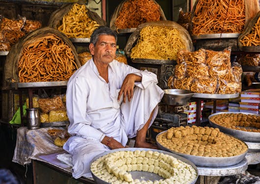 A market stall vendor stands with his colorful orange and yellow-hued food in Jaipur, India.