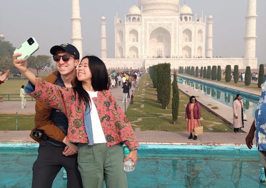 A couple poses and takes a selfie in front of the Taj Mahal in Agra, India.