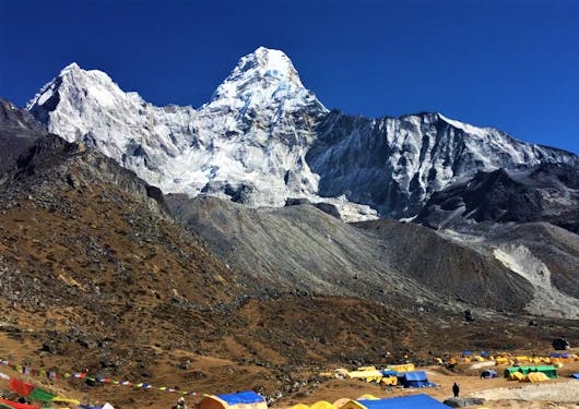 A camp along the Amadablam Base Camp trail is shown at the foot of towering mountains.
