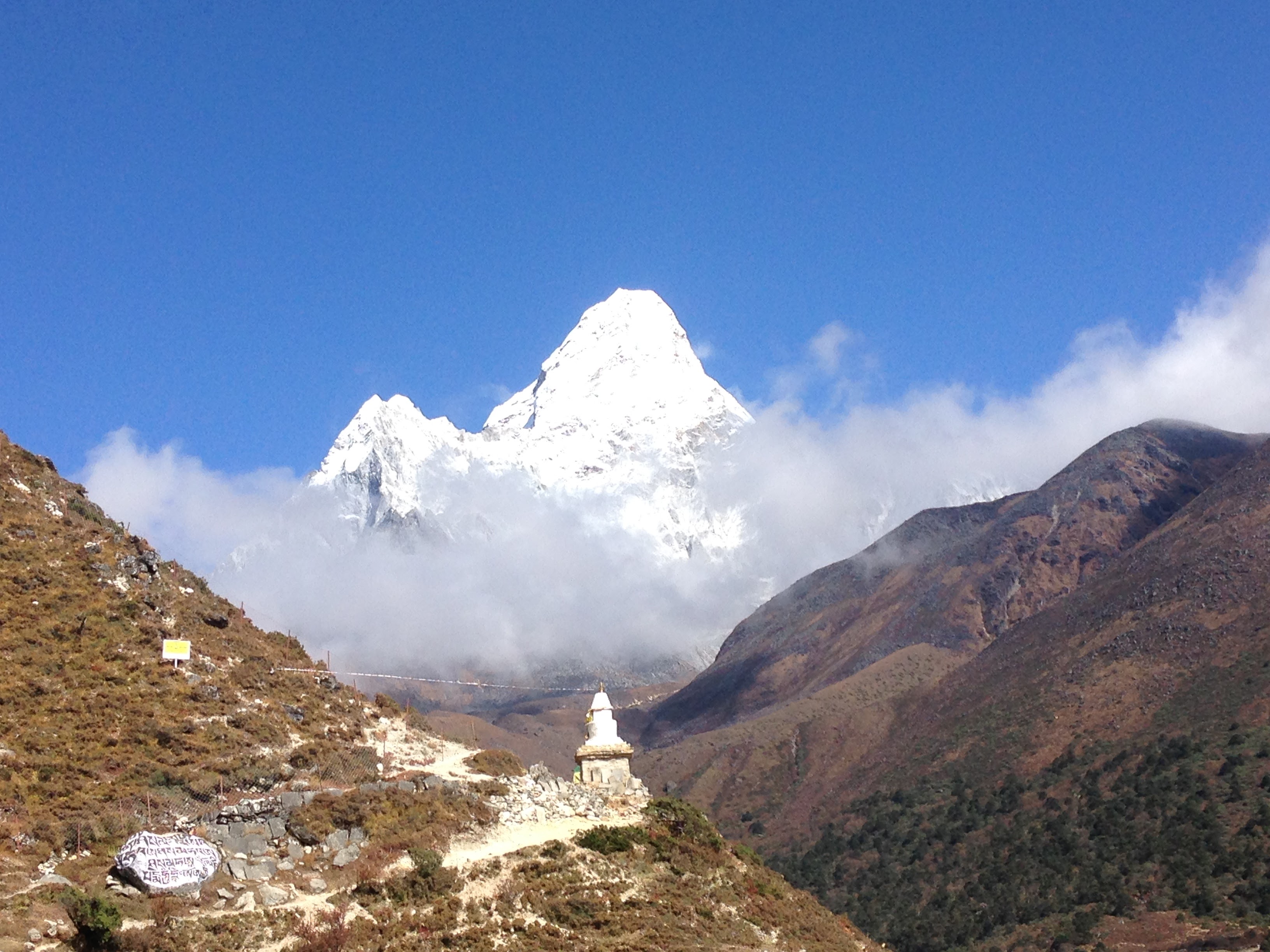 A temple with a white stupa with the towering Mount Everest in the background.