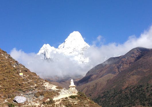 A temple with a white stupa with the towering Mount Everest in the background.