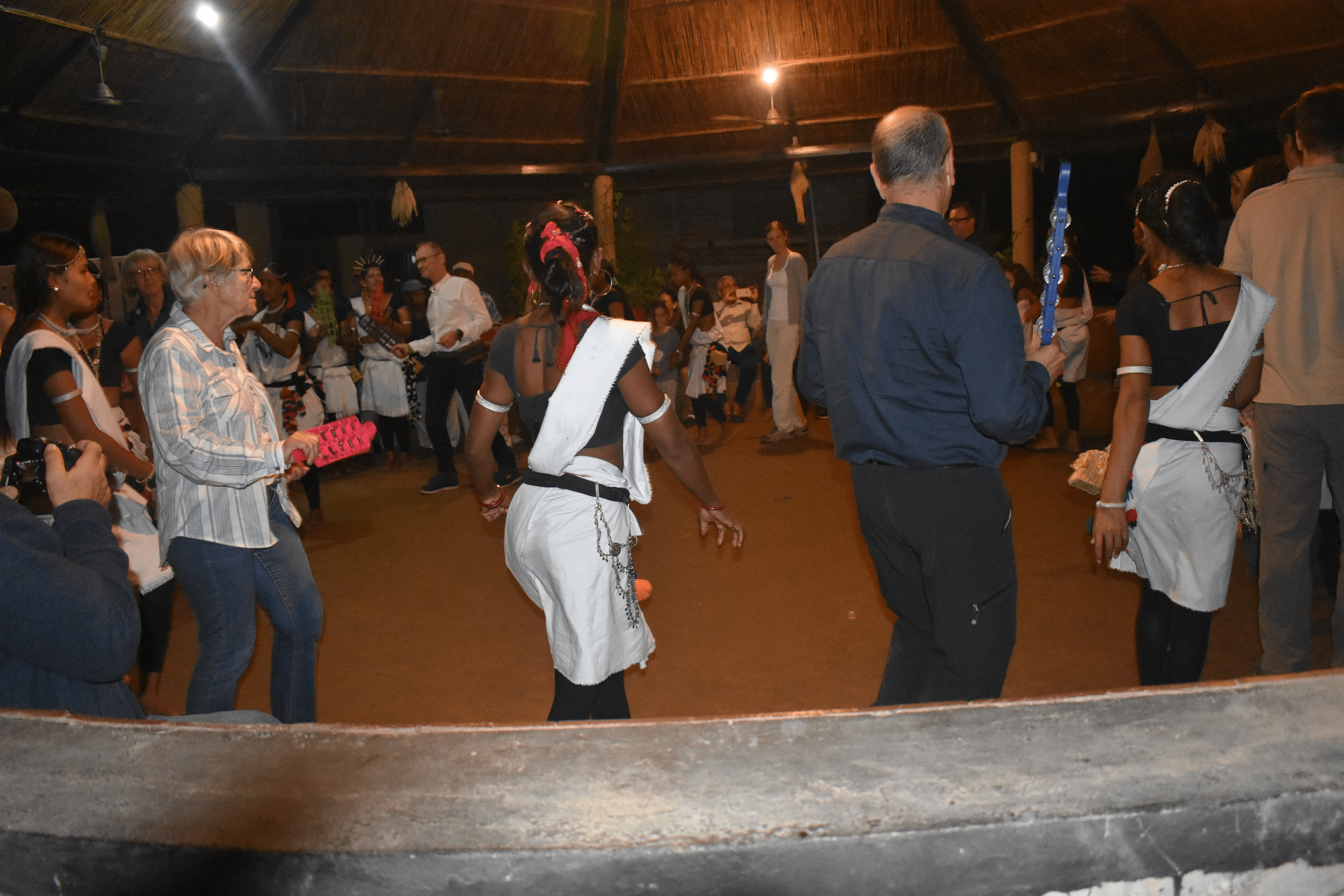 A group of travelers and locals perform a traditional evening Tharu dance in Chitwan, Nepal.