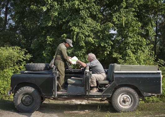A traveler and guide stop in the safari jeep to look at a map.