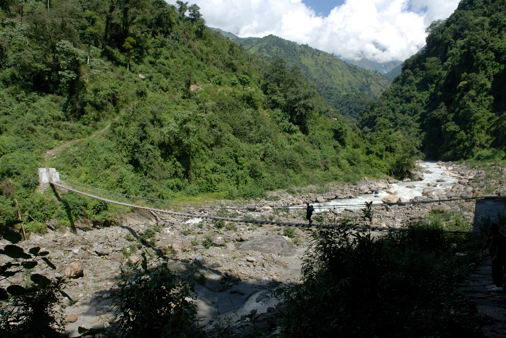 A new bridge is shown crossing a river bed in Nepal along the Annapurna Panorama Trek.