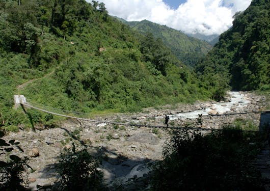 A new bridge is shown crossing a river bed in Nepal along the Annapurna Panorama Trek.