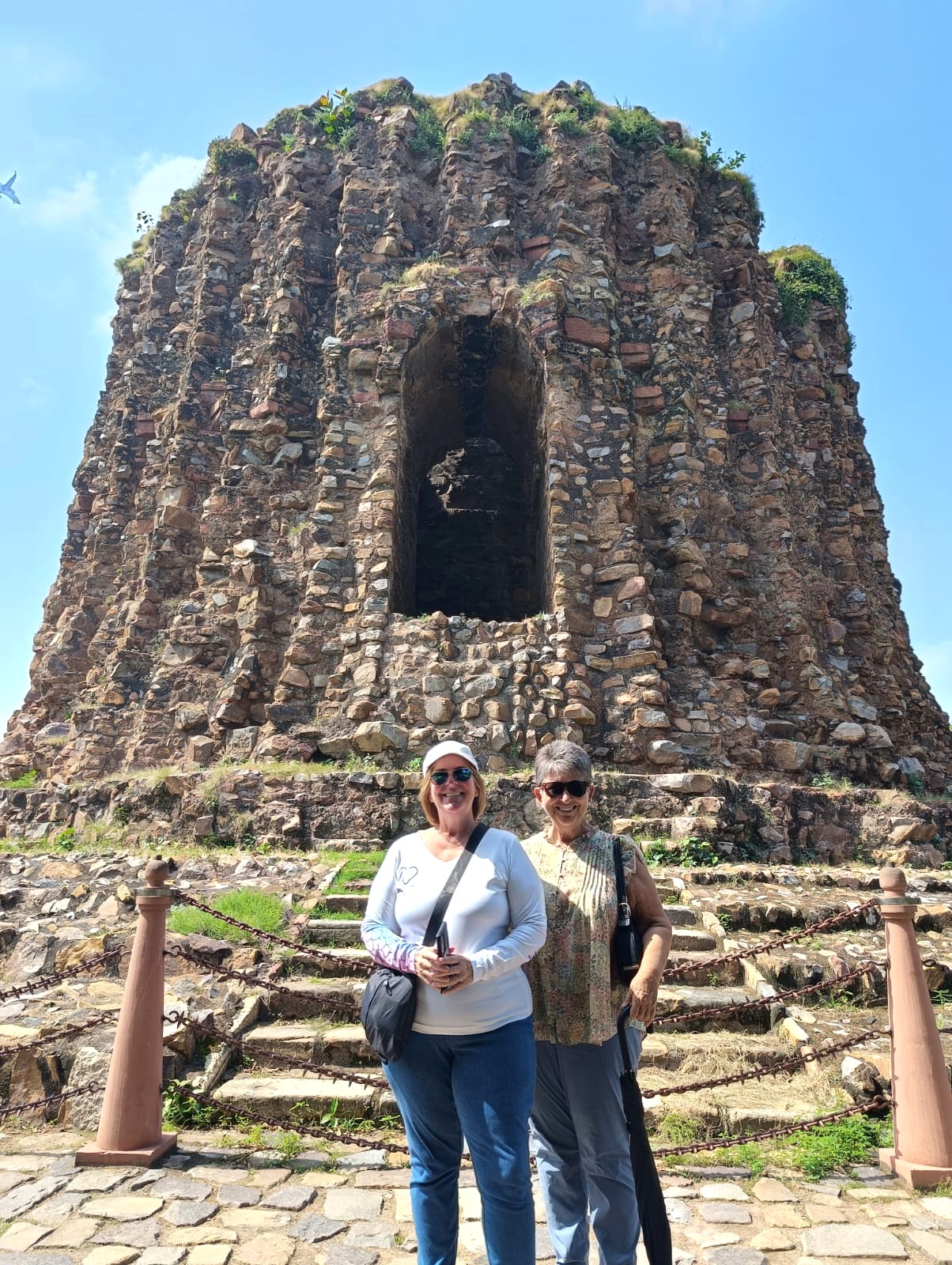 A couple stands in front of a stone structure in Delhi, India on a cultural tour.