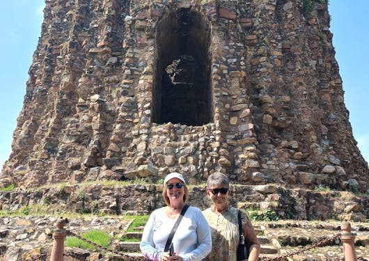 A couple stands in front of a stone structure in Delhi, India on a cultural tour.