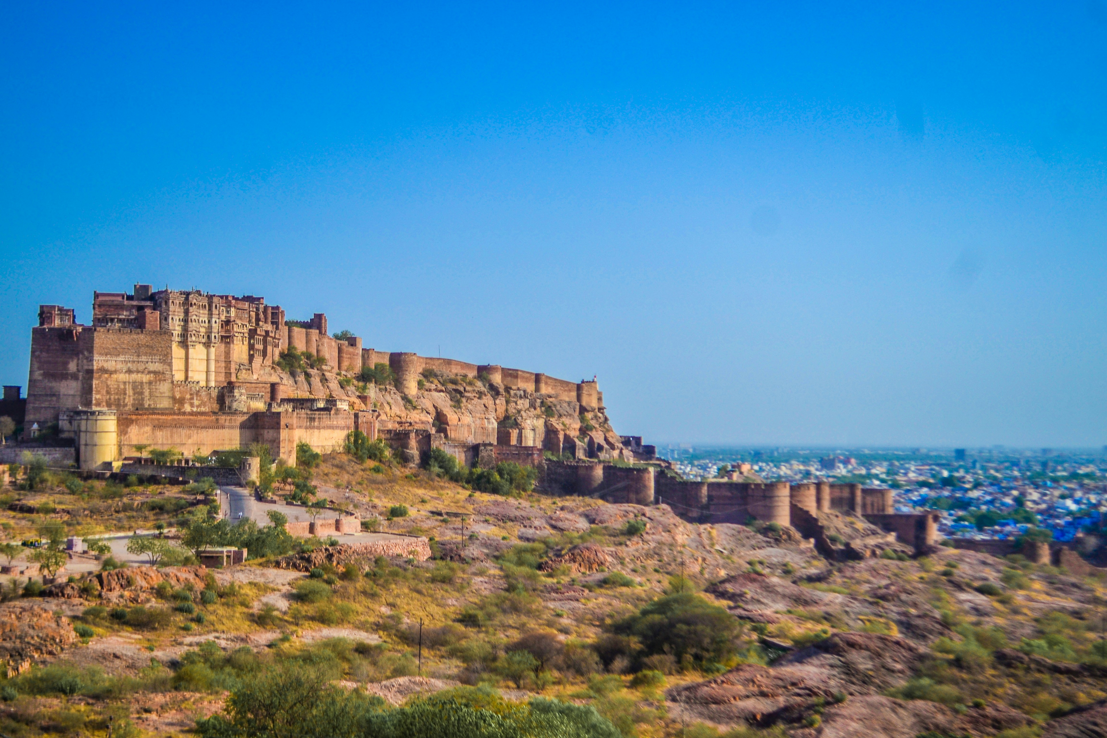A fort in India is shown against a bright blue sky.