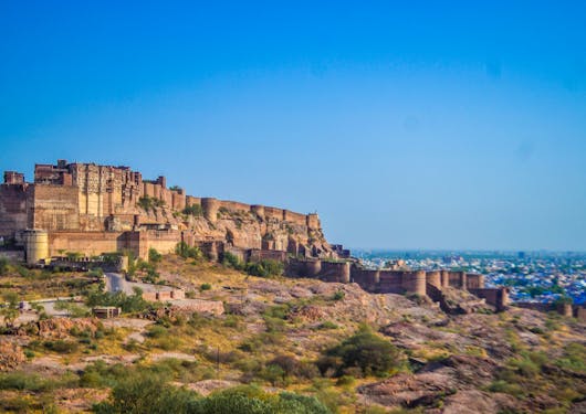 A fort in India is shown against a bright blue sky.