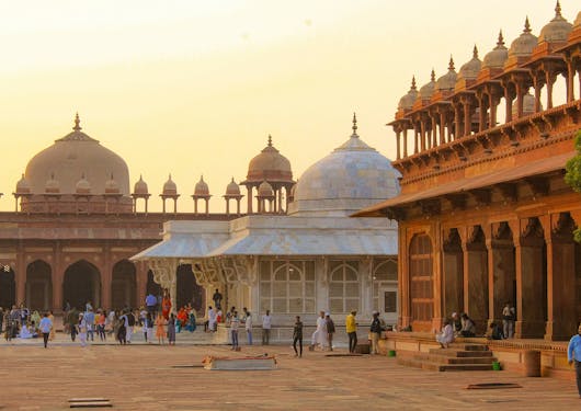 A mix of red, white, and beige palace or fort buildings are shown in India.