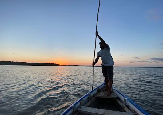 A local Kenyan man paddles a canoe at sunset.