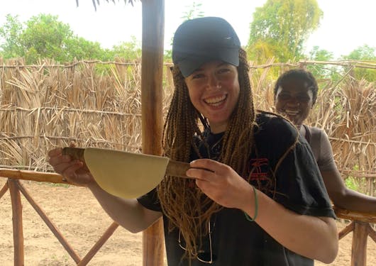An adult female traveler holds up a dish while visiting the local Watamu Village in Kenya.