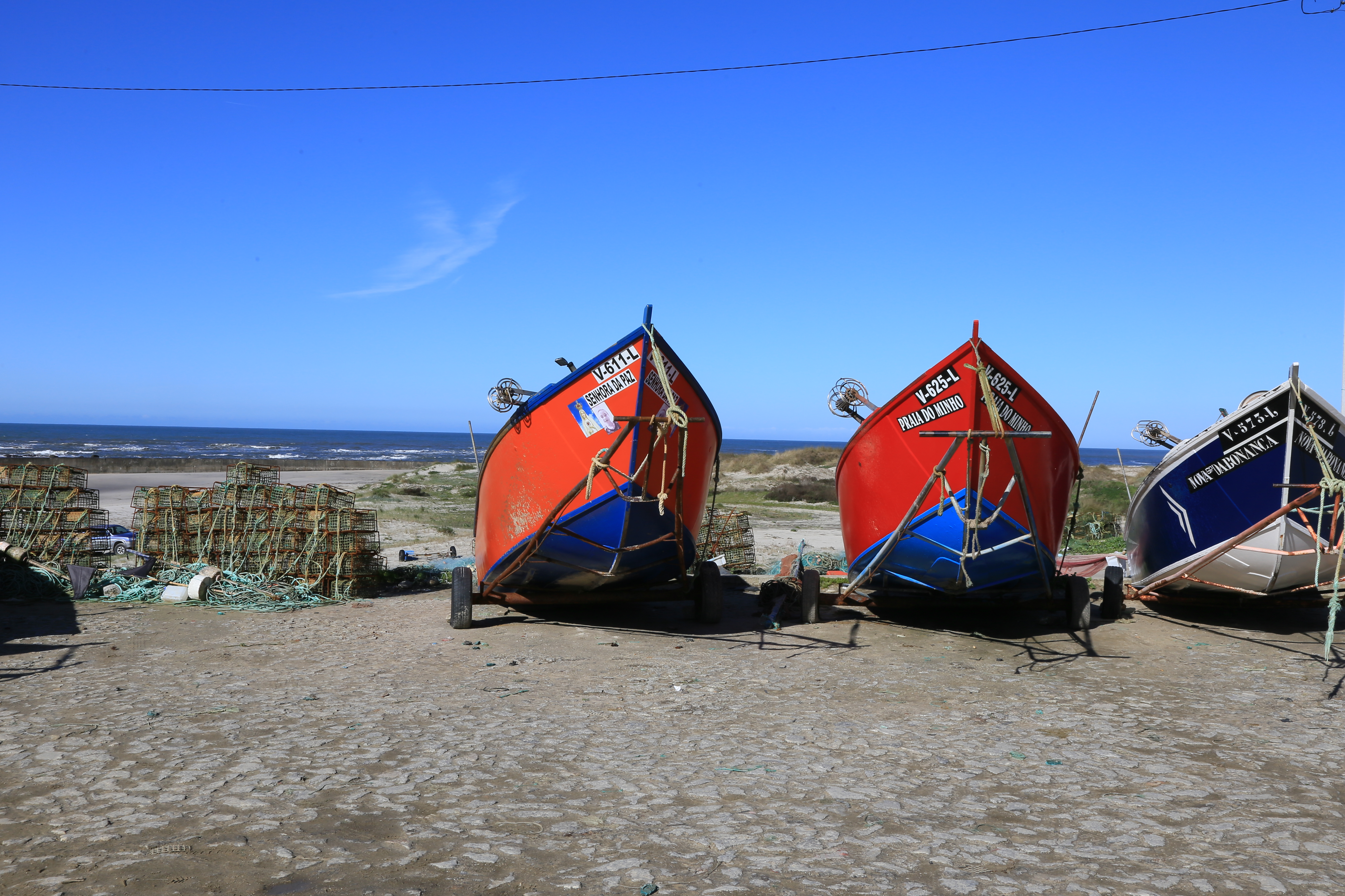 Red fishing boats are shown on the sand of Portugal's Costa Verde.