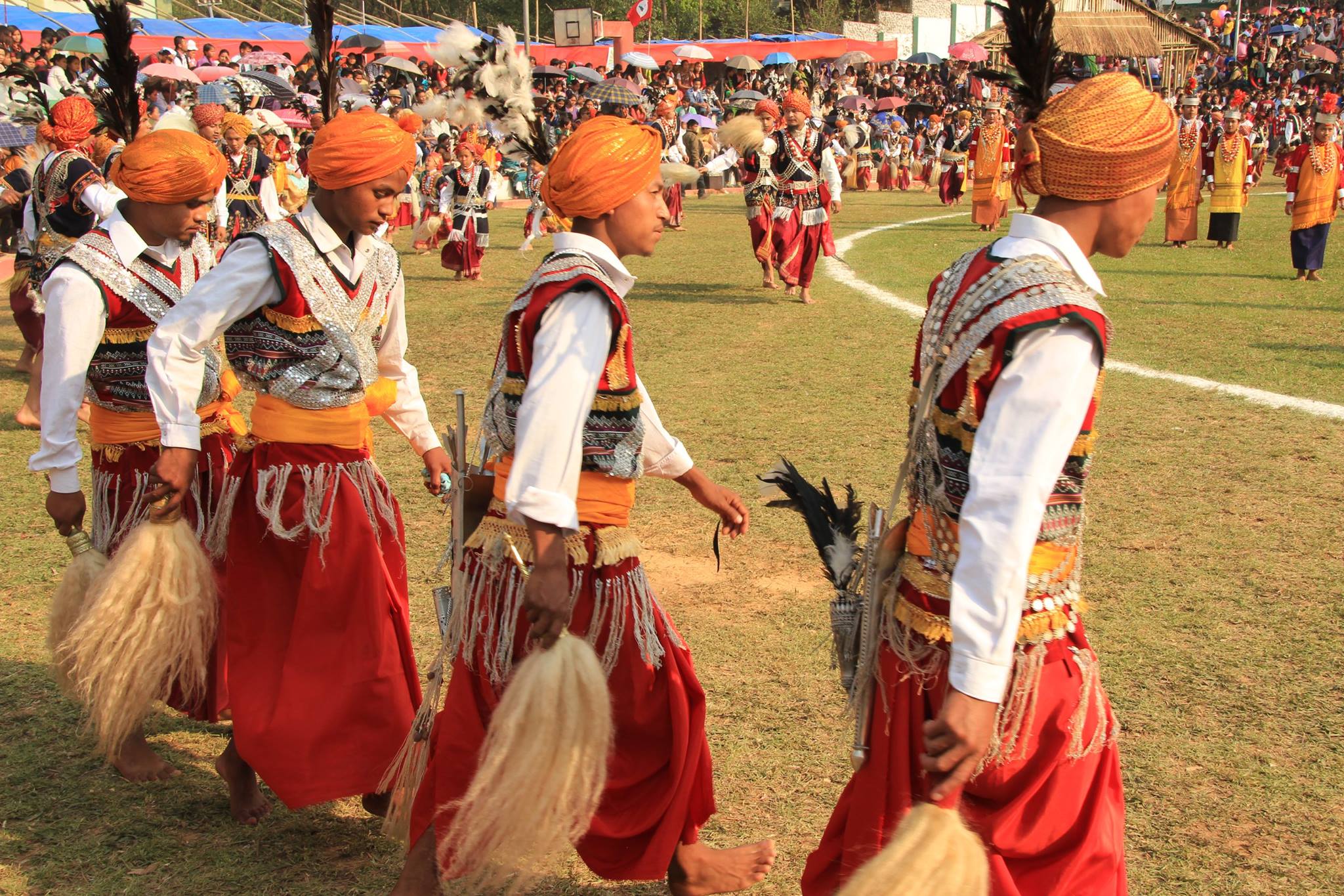 Indian men in traditional, colorful clothes perform the Khasi dance.