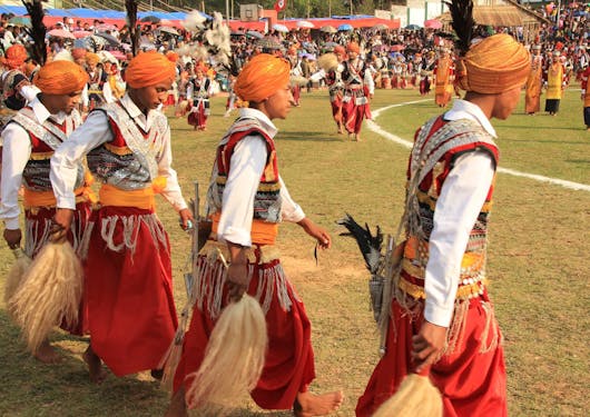 Indian men in traditional, colorful clothes perform the Khasi dance.