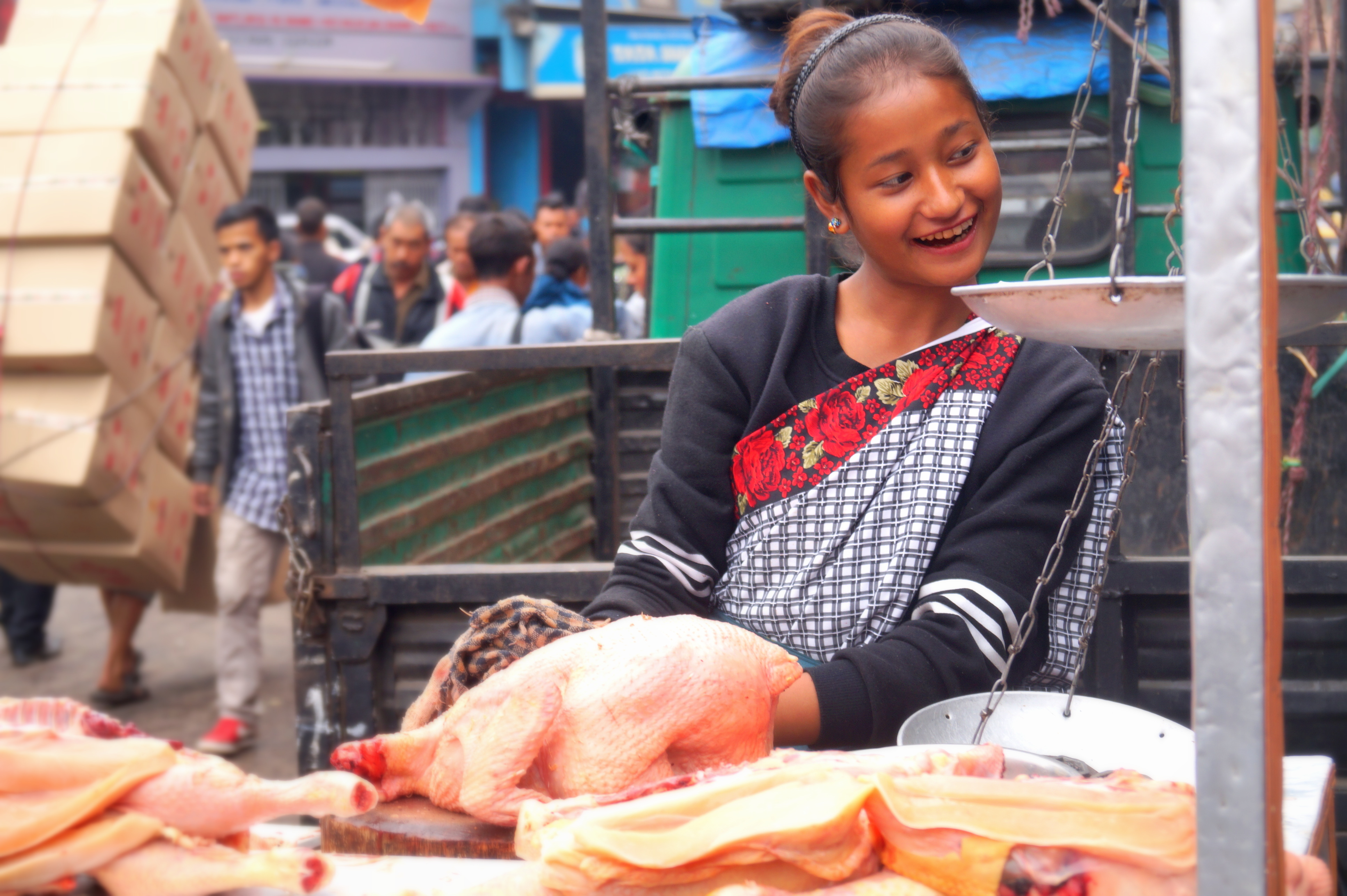 A young Indian woman stands behind her butcher ware at a market.