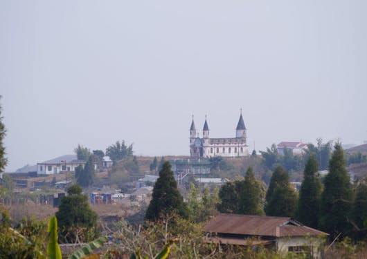 In India, the Cherrapunjee castle is in the distance under a grey sky.