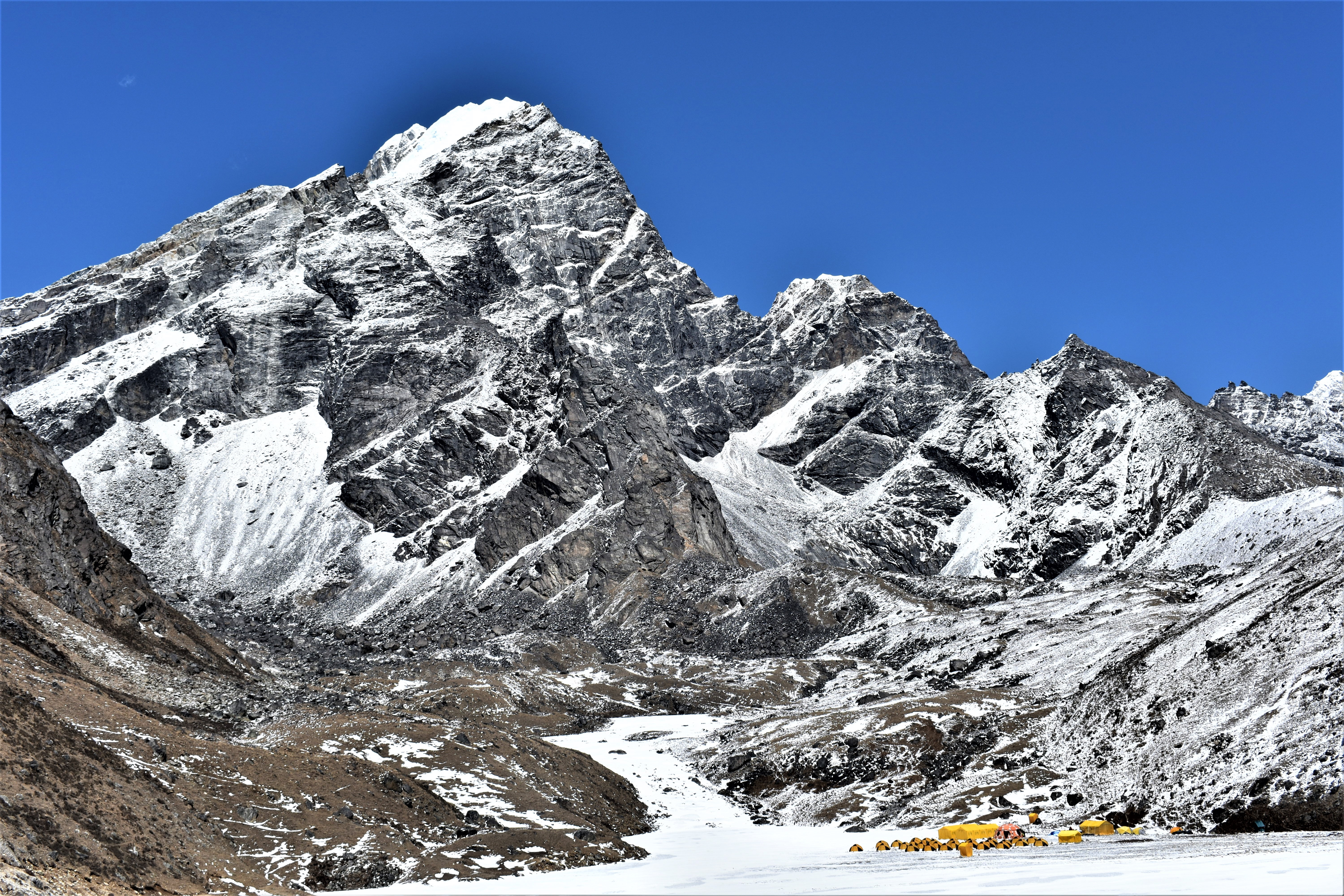 A mighty snow-capped mountain is prominently displayed against a perfectly blue sky.