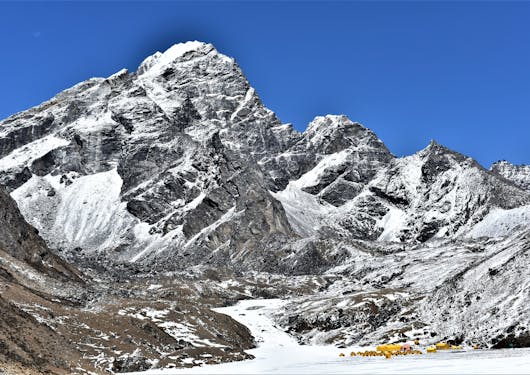 A mighty snow-capped mountain is prominently displayed against a perfectly blue sky.