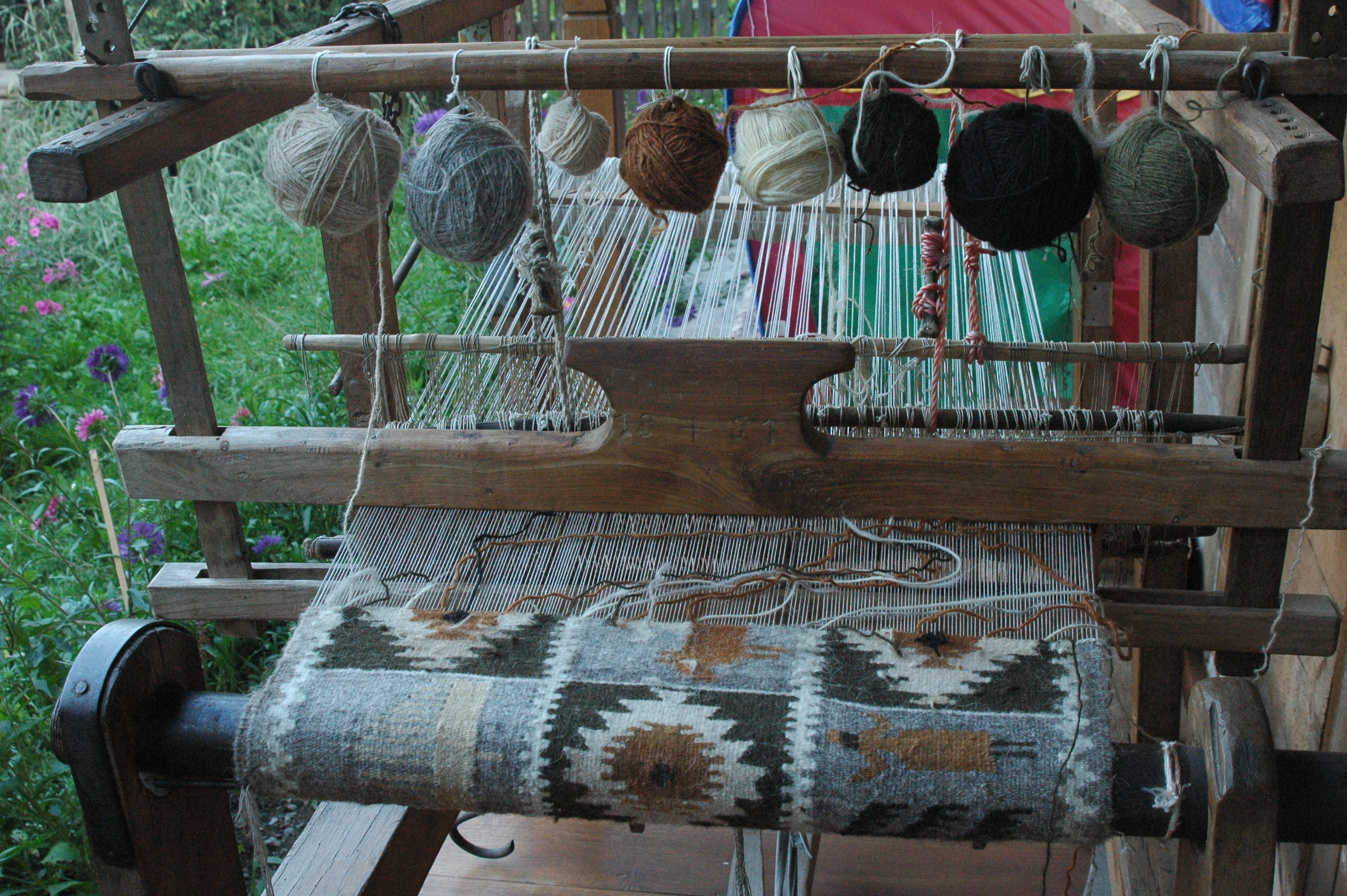 In Maramures, Romania, a traditional weaving mill is shown with balls of yarn on it as a design is being woven. 