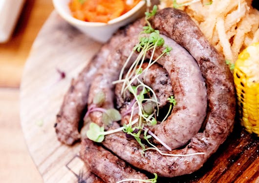Grilled meat on a wooden platter is displayed next to some other small bites on the Cape Wineland tour in South Africa.