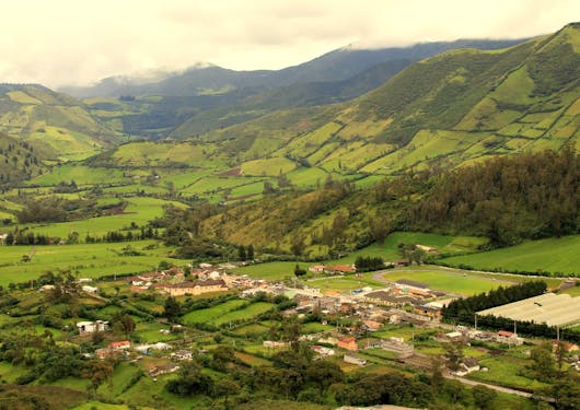 The small village of Nono sits nestled at the bottom of a shallow valley, surrounded by rolling green hills in Ecuador.