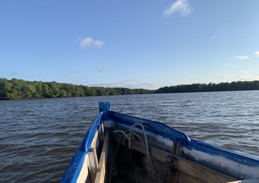 A small boat is out in Mida Creek, Kenya, with open water in front of it and greenery on a land mass in the distance.