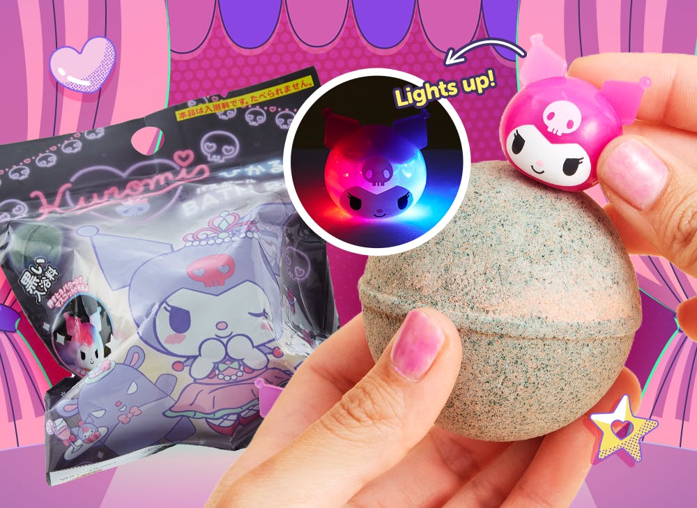 A hand holding a silver bath bomb up to the camera with the pink light up kuromi toy on top. 