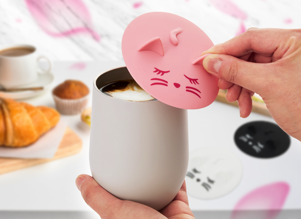 A hand holding a cup and placing a cat cup cover on top of the cup