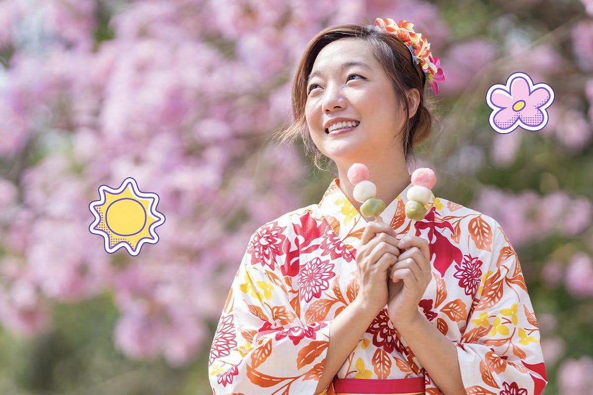 Japanese girl in a kimono eating dangos by the cherry blossoms