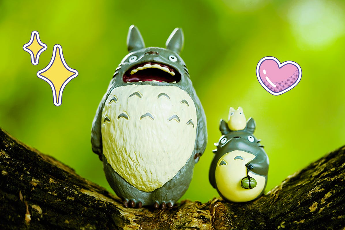 Two Totoro figures standing on a trip against a green background 