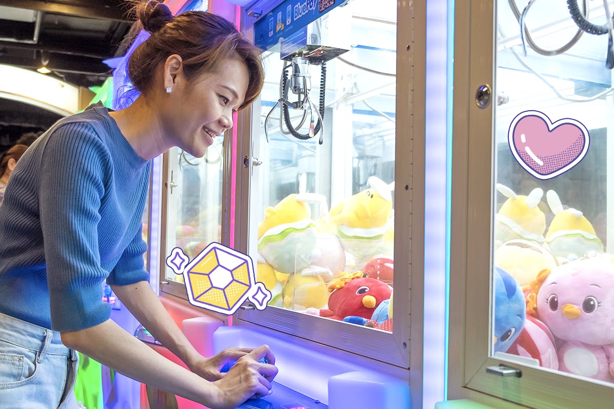 A young asian girl playing a crane game at an arcade 