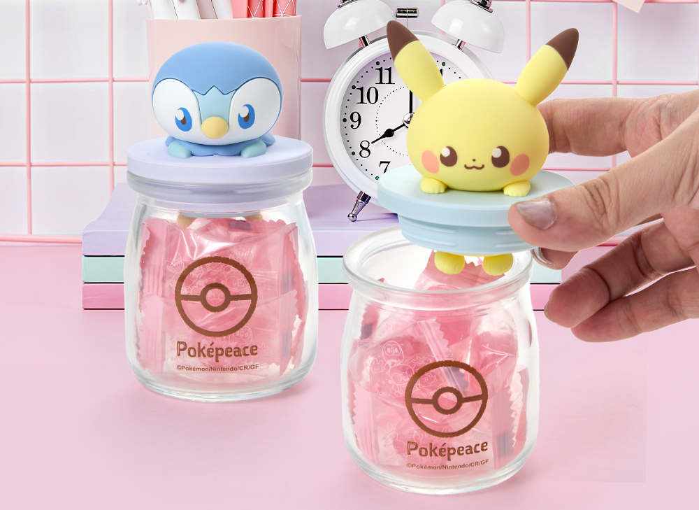 Two glass PokePeace candy jars sit on a pink table.