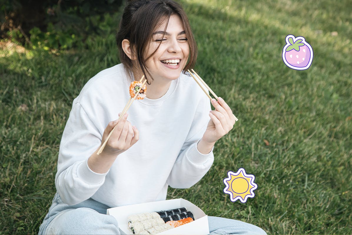 A girl enjoys a sushi bento at a park.